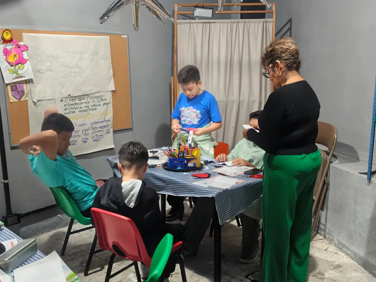 Niños aprendiendo y realizando actividades con su maestra en la escuelita