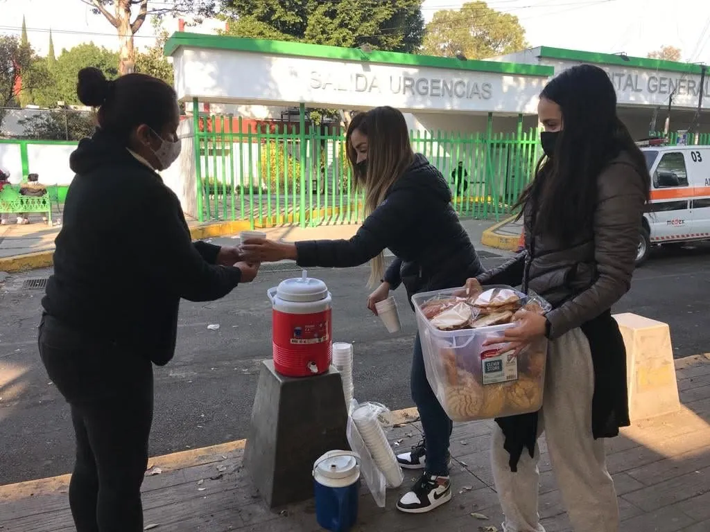 Integrantes de Talita Cumi entregando alimentos afuera de un hospital